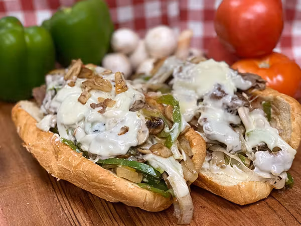 Cheesesteak subs topped with melted mozzarella, grilled onions, and green peppers at Manny & Olga’s in Georgetown.