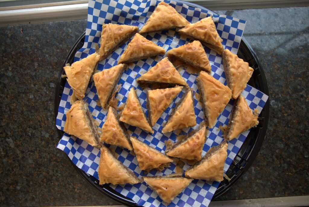 Delicious pieces of baklava Delicious pieces of baklava arranged on a blue and white checkered paper, showcasing its flaky pastry and rich filling.
