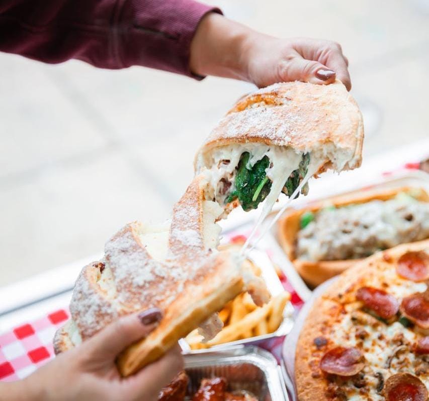 This image captures a calzone being pulled apart This image captures a calzones being pulled apart to reveal its melted cheese and spinach filling, creating a mouthwatering cheese stretch.