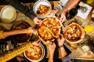 Group of people enjoying various pizzas at a catering event.