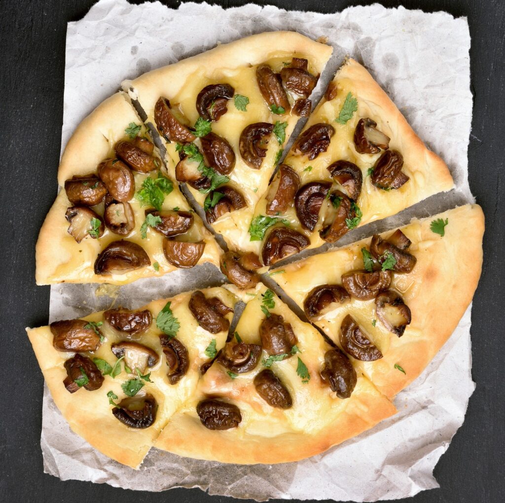 Fresh mushroom, spinach, and feta pizza on a paper plate.