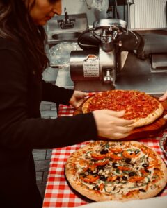 Freshly made pizzas being prepared and served in the kitchen at Manny & Olga’s.