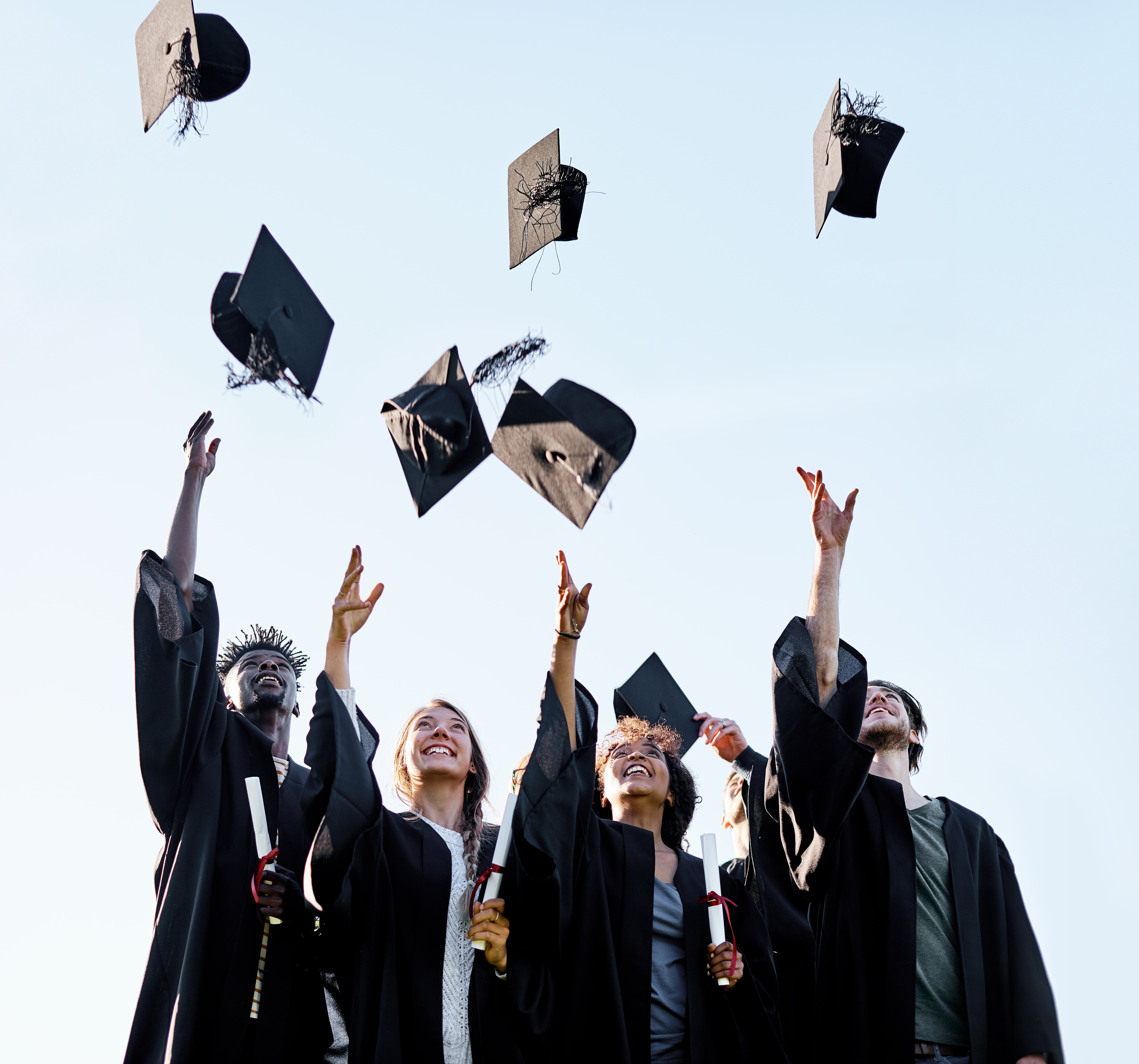 Shot of a group of students throwing their hats in the air on graduation day.