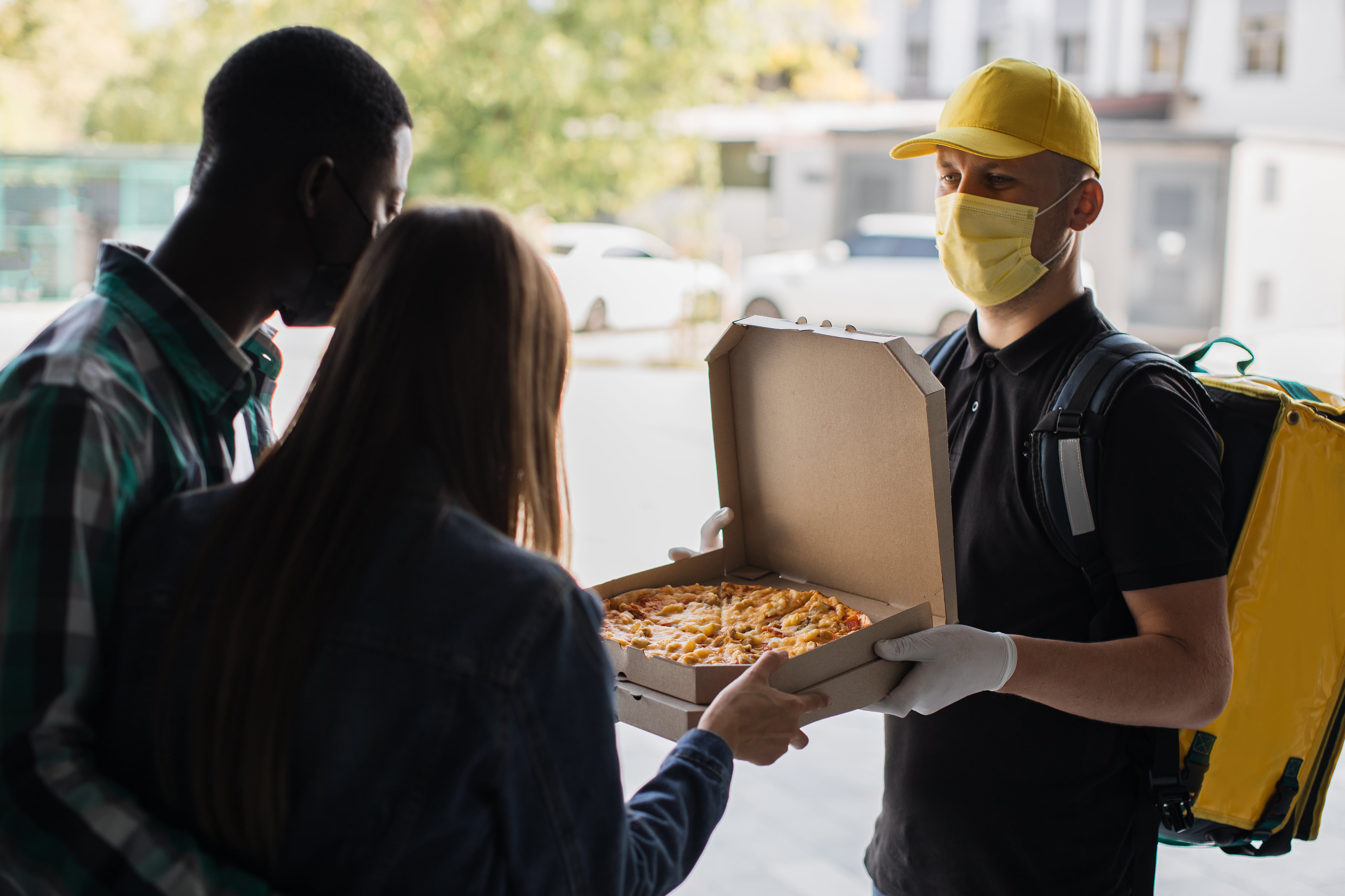 A pizza delivery driver delivering a hot pizza to a happy customer.