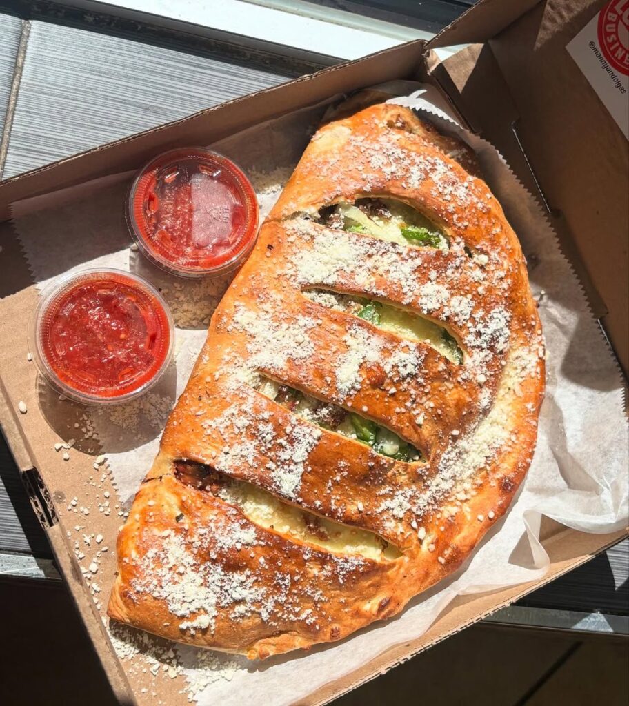 Golden baked calzone topped with parmesan and served with marinara sauce from Manny & Olga’s.