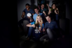 A group of people huddled to watch a football game in the living room.