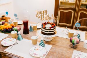 Image of a birthday party dinner table with cake, sweets, and celebratory accessories.