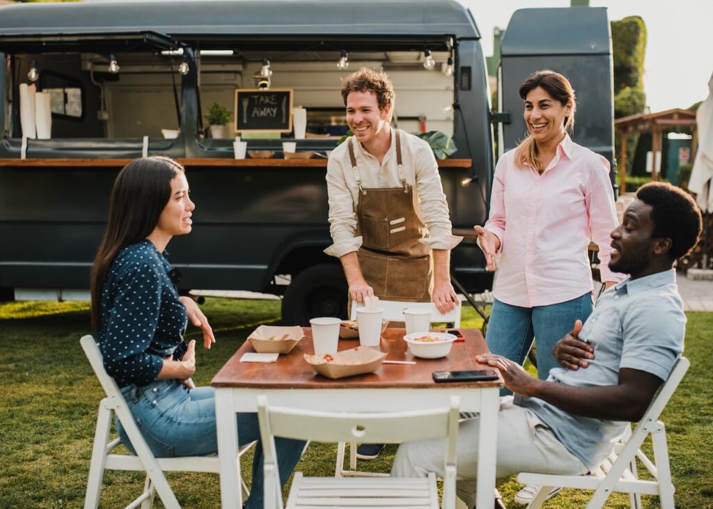 A scenic shot of a group of people enjoying food from a tailgate caterer.