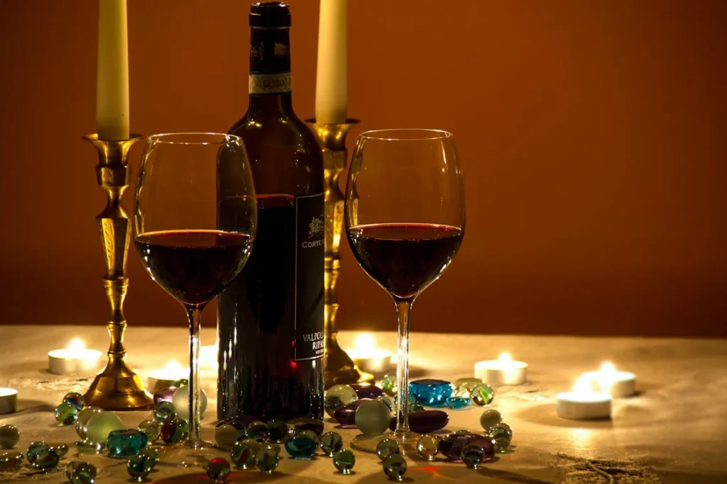 Romantic close-up of two wine glasses on a candle-lit Valentine’s Day table setup for a cozy date night.