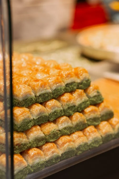 Close-up of stacked Baklava, a traditional Greek dessert with layers of filo, honey, and nuts.
