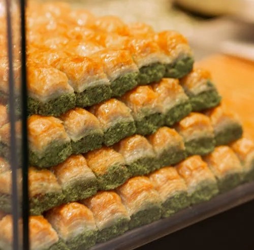 Close-up of stacked Baklava, a traditional Greek dessert with layers of filo, honey, and nuts.
