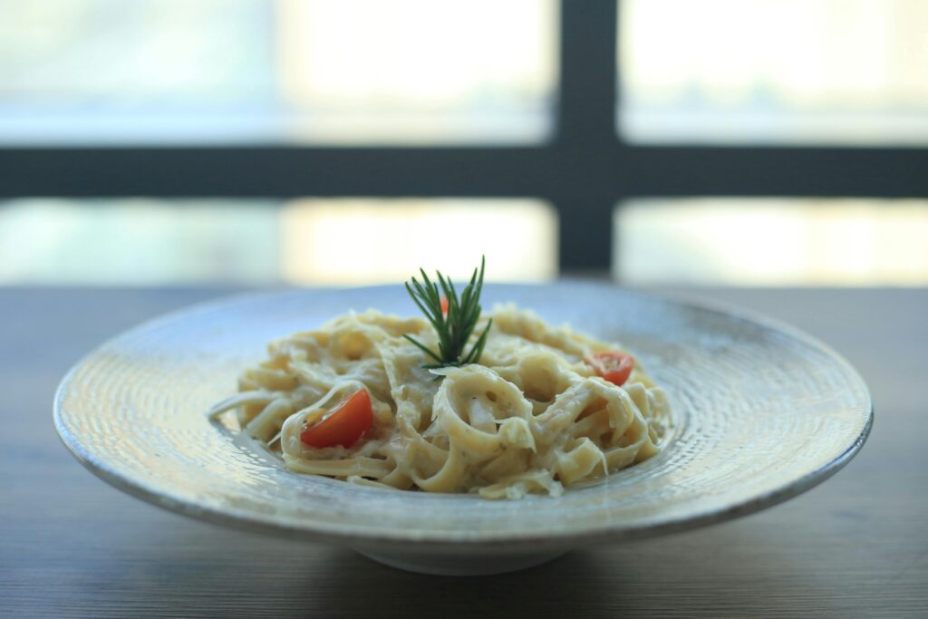 Close-up of creamy fettuccine Alfredo topped with fresh herbs.