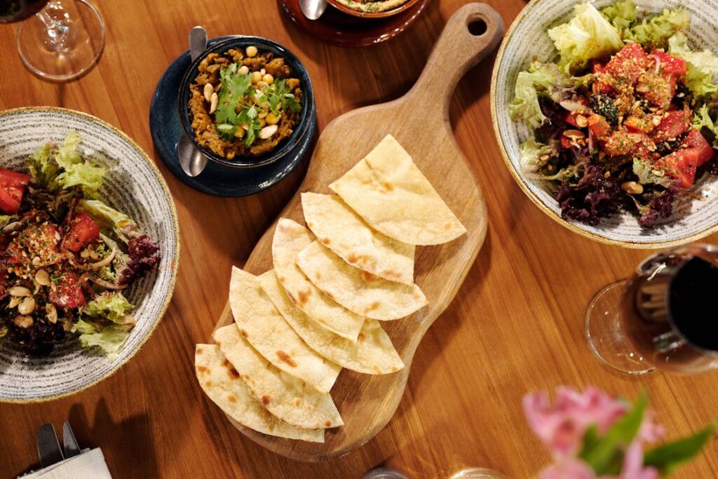 Freshly baked pita slices served with vibrant salad and savory dip, showcasing Mediterranean flavors at Manny & Olga’s.