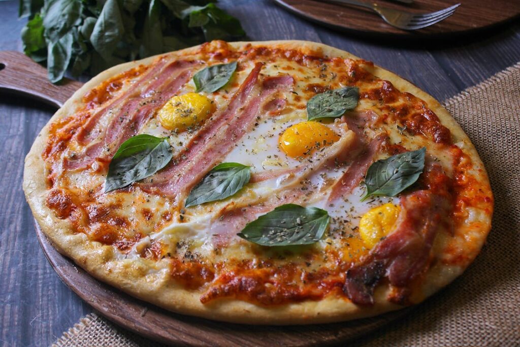 Close-up shot of a hot pizza with eggs and ham as toppings.