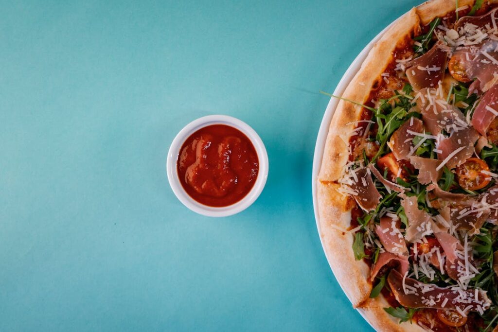 A flat-lay shot of a meat pizza paired with a spicy dipping sauce, showcasing a bold flavor combination.