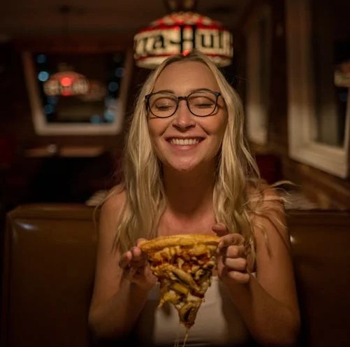 A person tries a topping-heavy cheesy slice of pizza at the best pizzeria in Washington.
