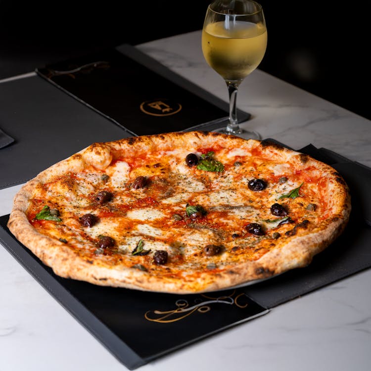 Neapolitan pizza with charred crust paired with a flute of champagne, ideal for elegant Easter celebrations.