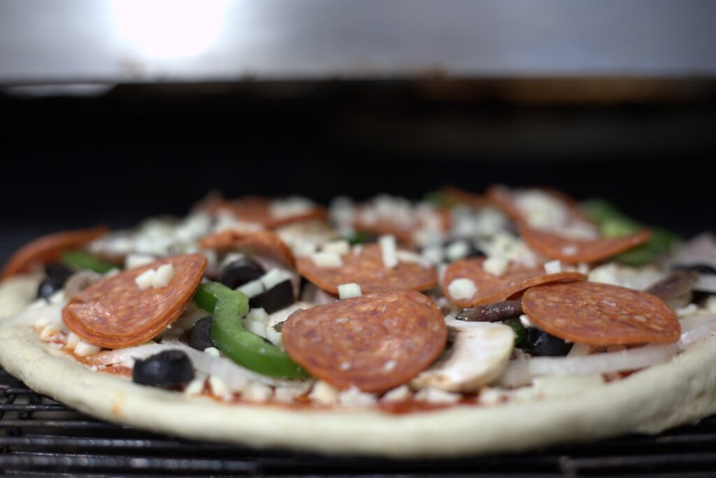 Manny and Olga’s pizza topped with pepperoni, olives, green peppers, onions, and cheese.