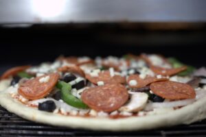 Manny and Olga’s pizza topped with pepperoni, olives, green peppers, onions, and cheese.