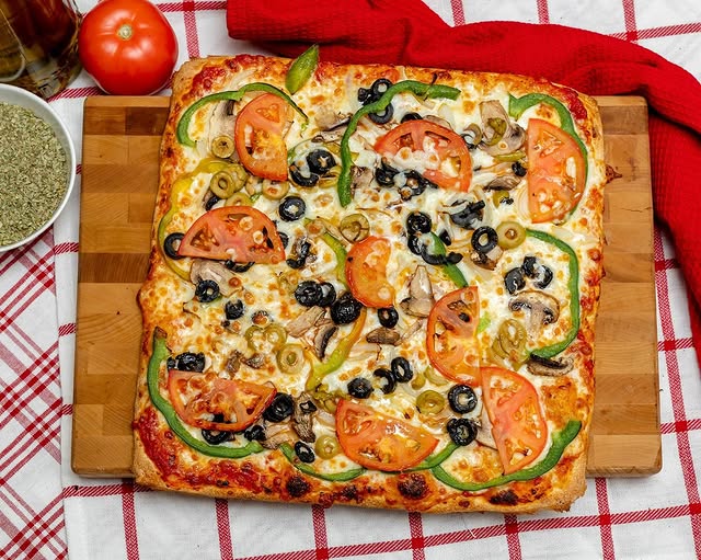 Square meat pizza with fresh tomato slices and sides from Manny & Olga’s, showcasing local flavor in Washington, DC.