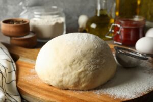 Cold-fermented pizza dough resting on floured surface, highlighting extended fermentation process.