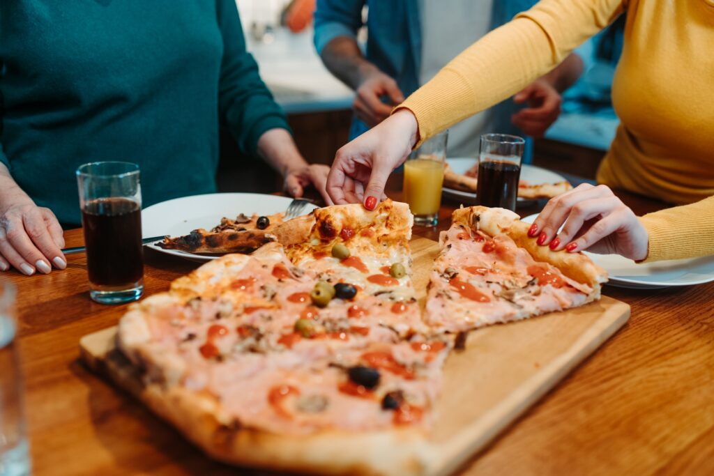Two people share slices of veggie pizza from Manny & Olga’s during National Pizza Party Day.