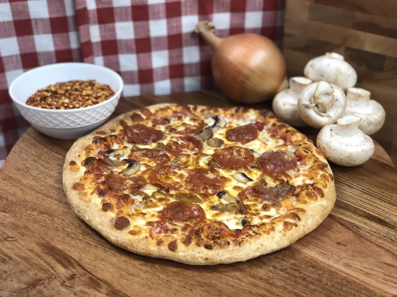 Manny & Olga’s Original Pizza with pepperoni, sausage, mushrooms, and mozzarella highlighting fluffy crust.