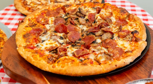 Close-up of a pepperoni and sausage pizza with melted cheese on a wooden serving tray.