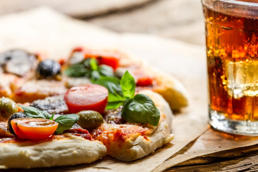 A cheesy pizza served with a chilled Coca-Cola on the side.