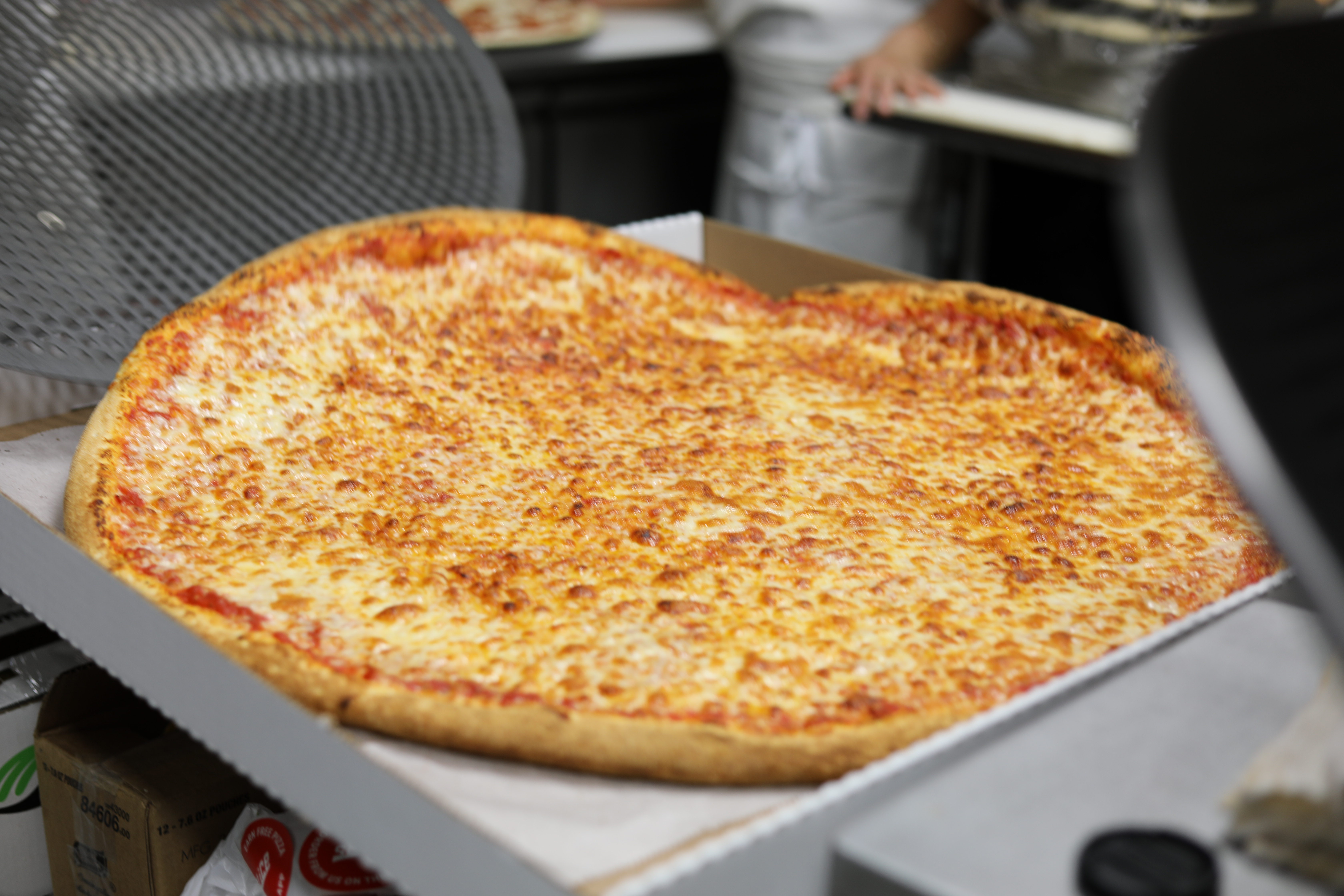 Thin-crust cheese pizza from Manny & Olga’s baked golden and served fresh in an open pizza box.