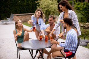 Group of young people cheering with cider and eating pizza.