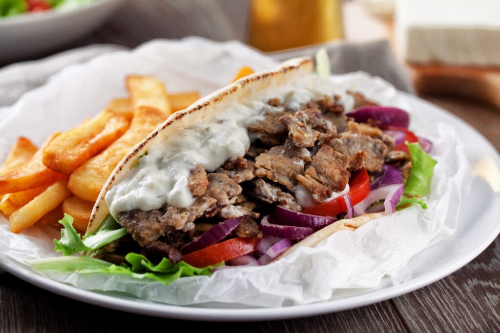 Greek Gyro with fries and salad on a plate.