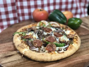 Chicken and tomato pizza on a wooden board with fresh vegetables