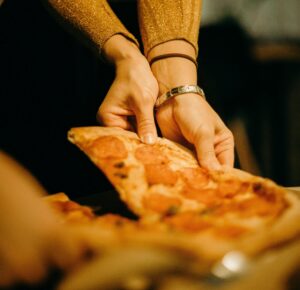 A person takes a slice of thick crust pizza.