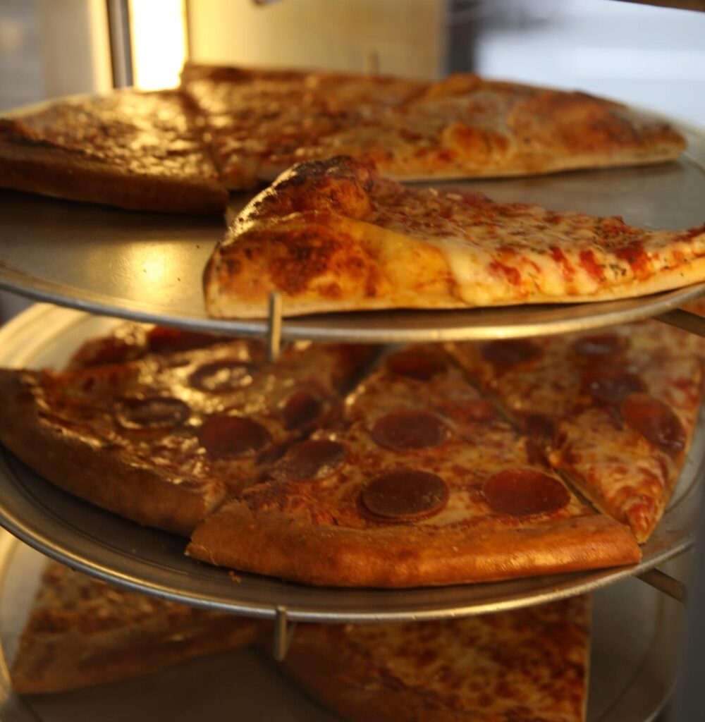 Hot pepperoni and cheese pizza slices stacked fresh at Manny & Olga’s for late-night cravings.
