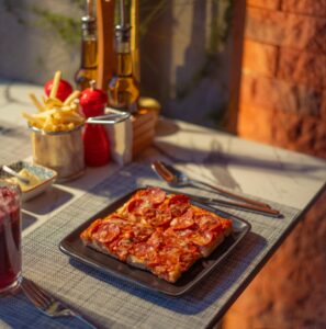 An aesthetically pleasing shot of a table with plated square pizza and other sides.