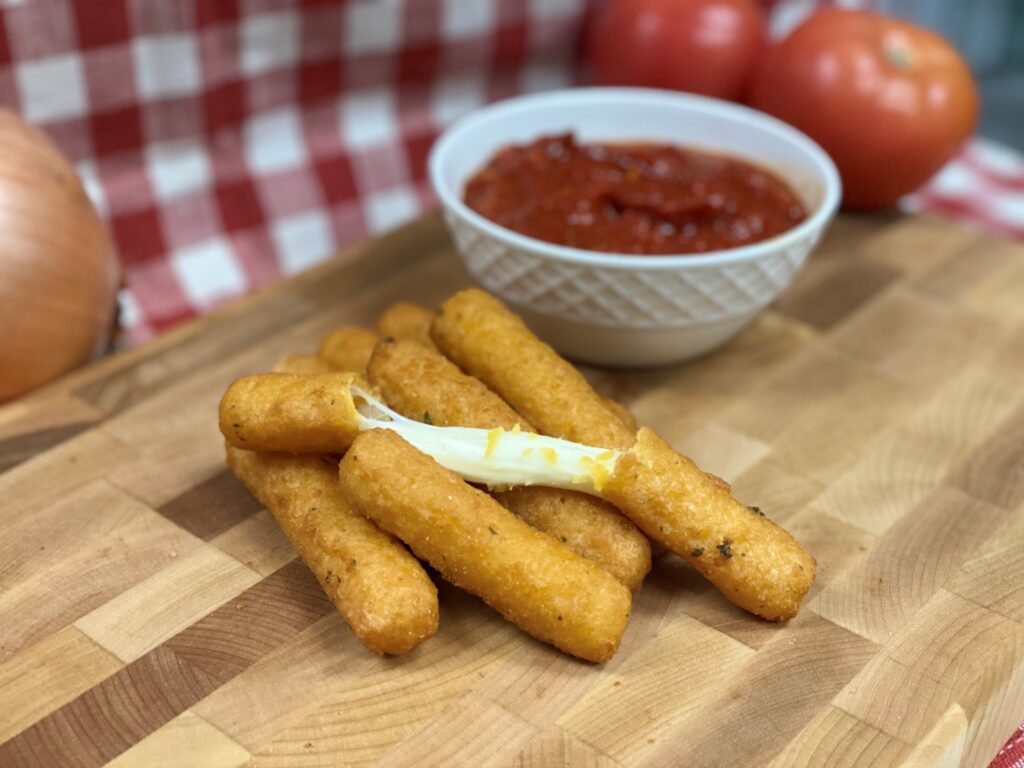 Manny and Olga’s fried mozzarella sticks with marinara sauce on a wooden serving board.