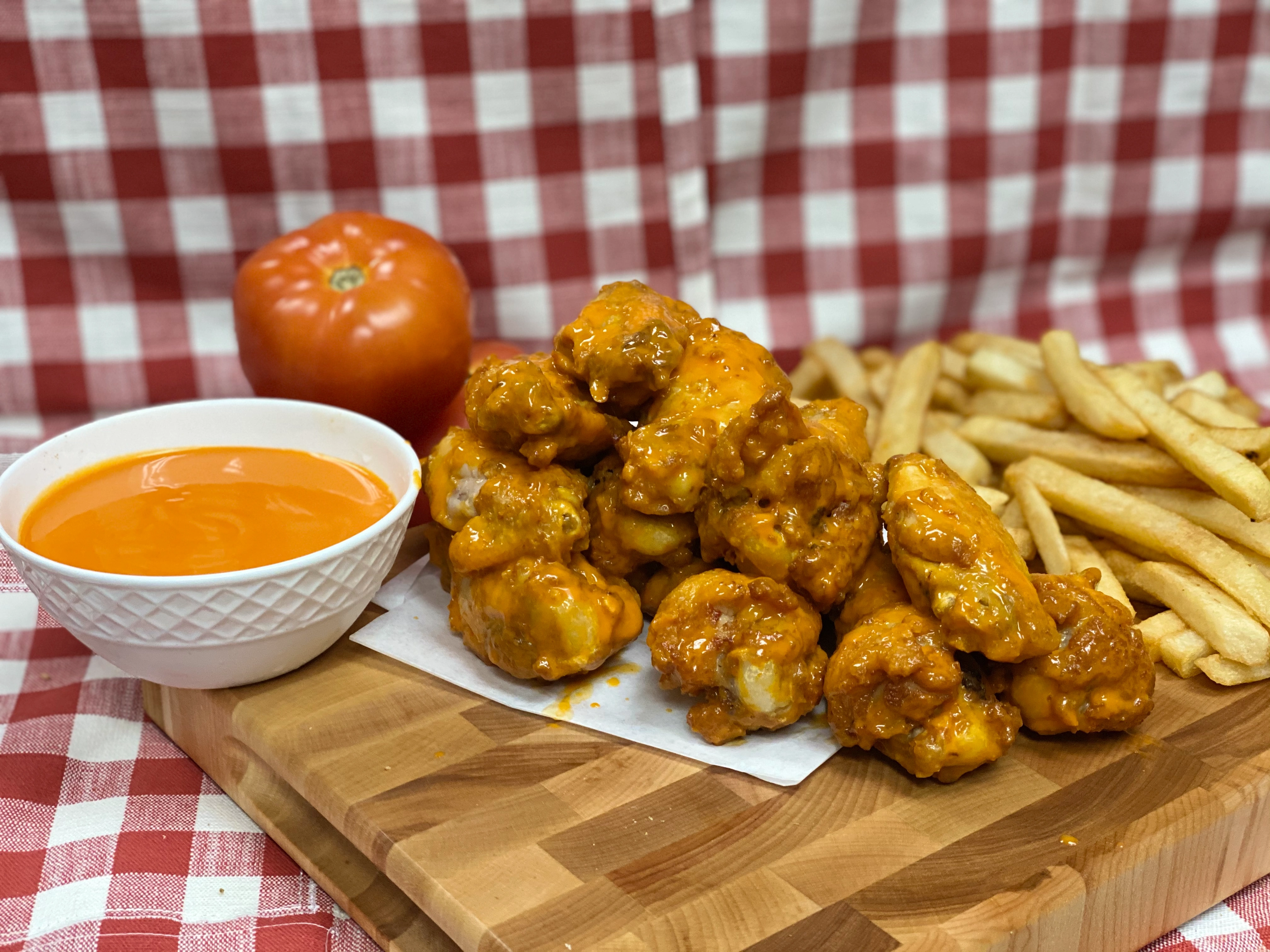 Manny & Olga's saucy chicken wings served with fries and dipping sauce.