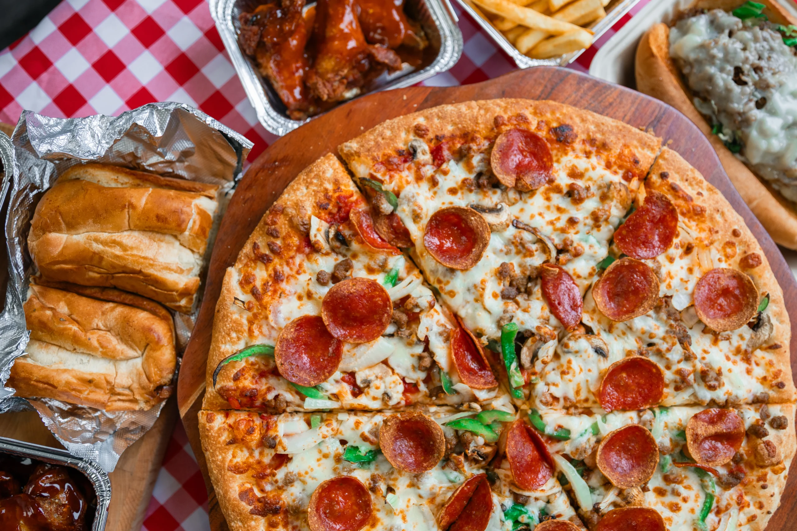 Manny & Olga's pepperoni pizza served with subs, wings, fries, and a loaded sandwich.