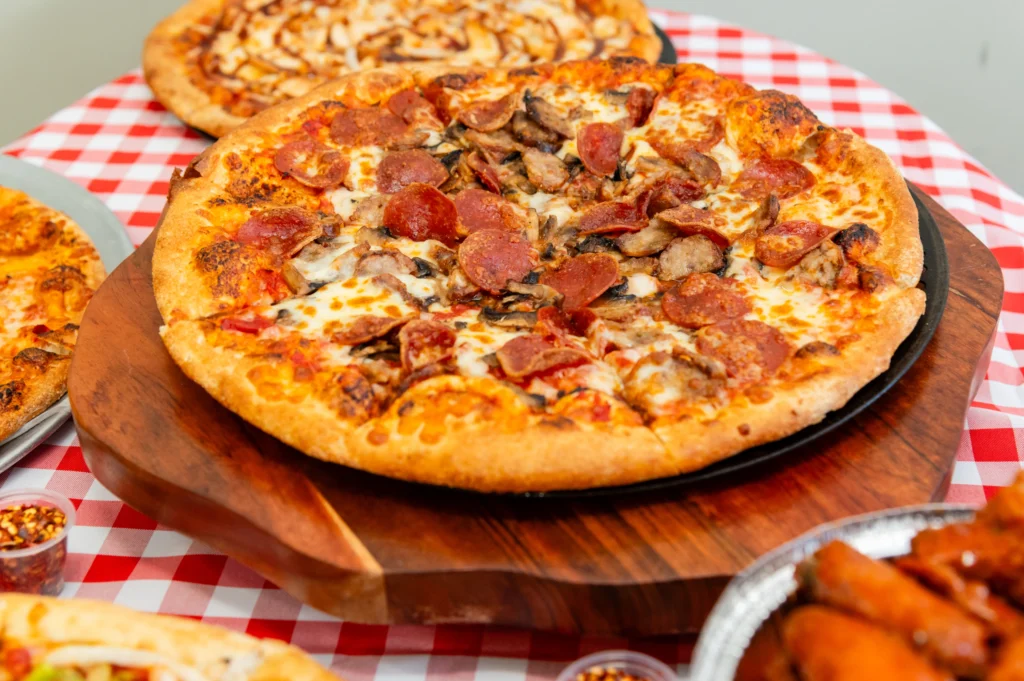 Manny & Olga’s pepperoni and sausage pizza served with wings and additional pizzas.
