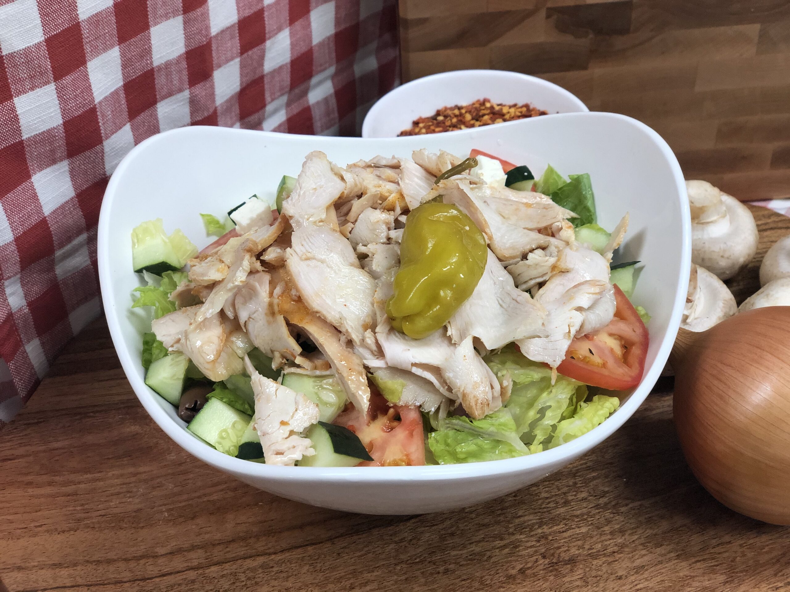 Manny & Olga’s chicken salad topped with sliced chicken, lettuce, cucumber, tomato, and a pepper.