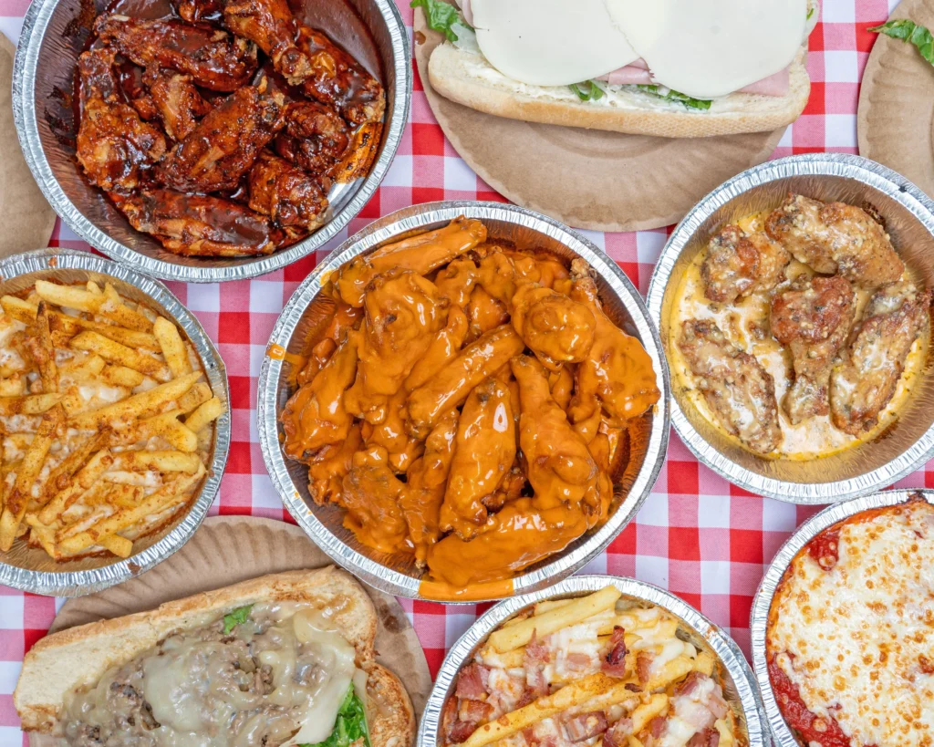 Manny & Olga’s spread with sauced chicken wings, loaded fries, subs, and a cheese pizza.