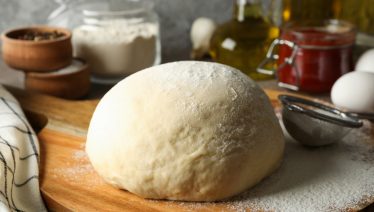 Cold-fermented pizza dough resting on floured surface, highlighting extended fermentation process.
