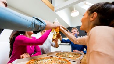 Family tossing with pizza slices around the table, celebrating Father’s Day in Manny and Olga’s way.