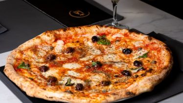 Neapolitan pizza with charred crust paired with a flute of champagne, ideal for elegant Easter celebrations.