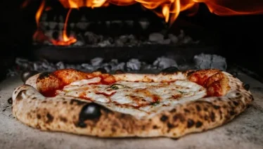 Neapolitan pizza baking in a wood-fired oven, highlighting fresh crust and melted cheese ideal for next-day recipes.