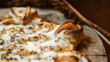 Cheesy shrimp-topped pizza with herbs and stuffed crust, ideal for an indulgent Mother's Day dinner from Manny & Olga’s.
