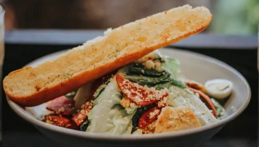 A sumptuous vegetable salad bowl with creamy garlic bread on the side.